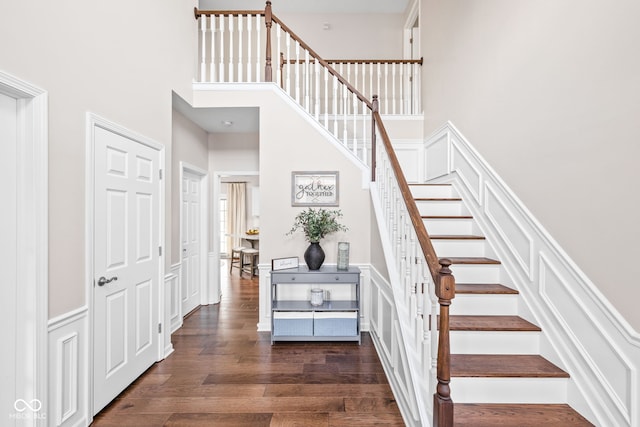 stairway featuring wood-type flooring and a towering ceiling