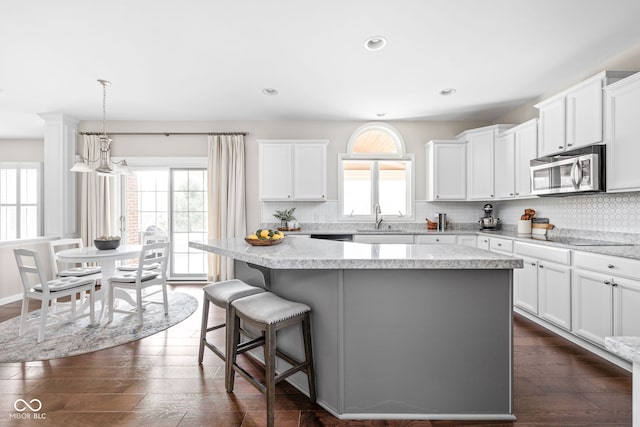 kitchen with a center island, white cabinetry, a healthy amount of sunlight, and sink