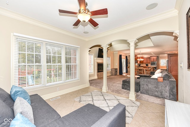 living room featuring a fireplace, ornate columns, a wealth of natural light, and crown molding