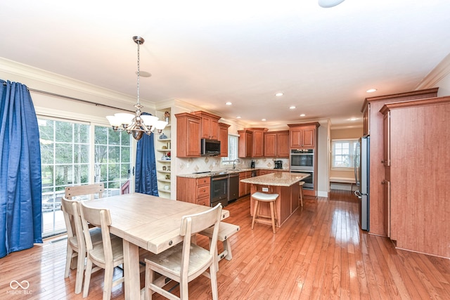 dining area featuring an inviting chandelier, ornamental molding, sink, and light hardwood / wood-style flooring