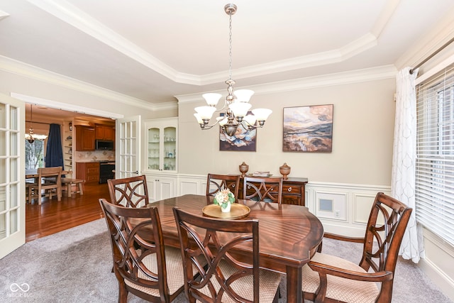 dining area featuring plenty of natural light, a raised ceiling, crown molding, and a chandelier