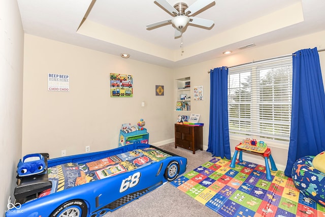 bedroom featuring carpet floors, a tray ceiling, and ceiling fan