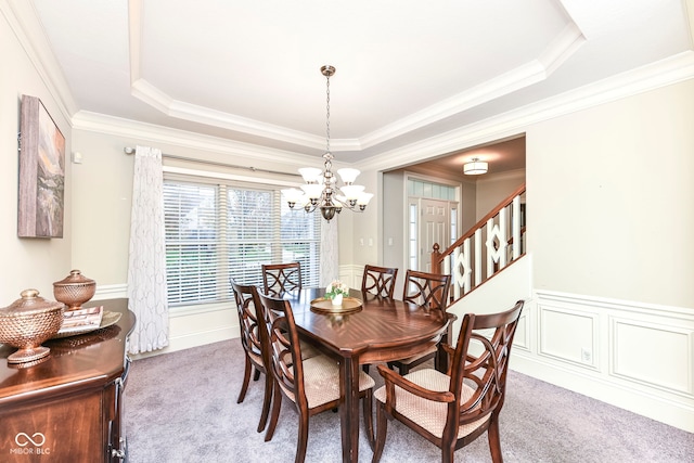 carpeted dining area featuring a tray ceiling, a notable chandelier, and ornamental molding