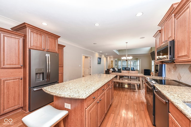 kitchen with appliances with stainless steel finishes, tasteful backsplash, ornamental molding, light hardwood / wood-style flooring, and a chandelier