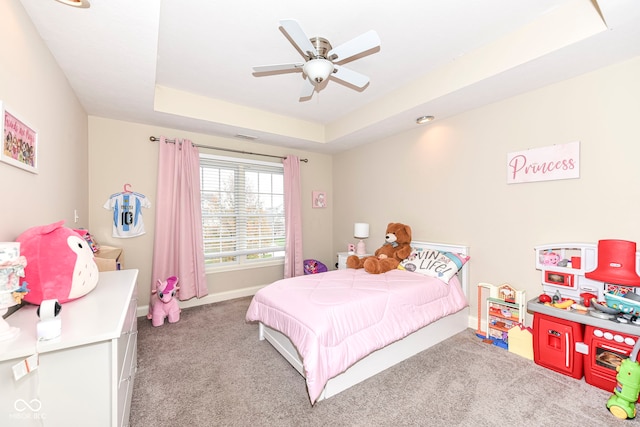 carpeted bedroom featuring ceiling fan and a tray ceiling