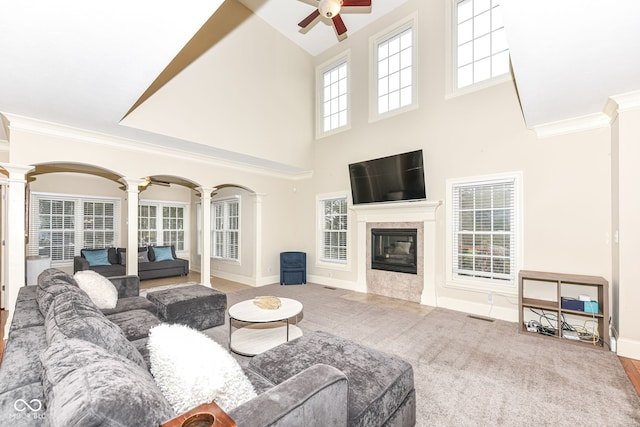 living room featuring a high ceiling, carpet flooring, ceiling fan, ornamental molding, and decorative columns