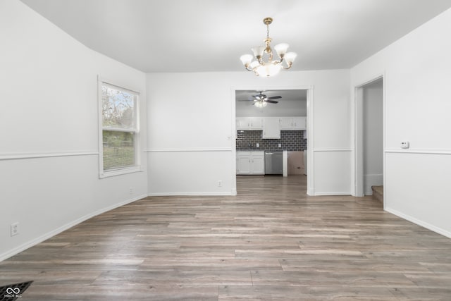 unfurnished dining area featuring ceiling fan with notable chandelier and light wood-type flooring