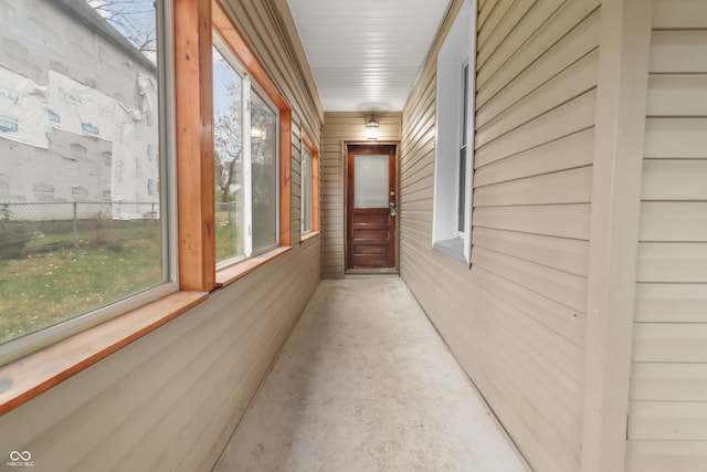 hallway featuring concrete flooring and wood walls