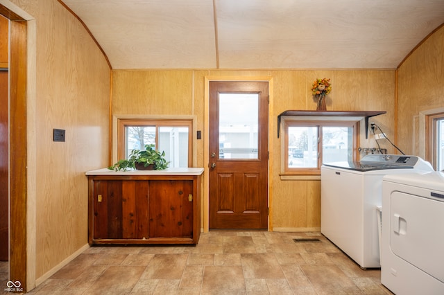 clothes washing area with separate washer and dryer and wooden walls