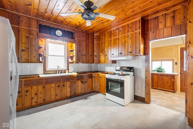 kitchen with white appliances, ceiling fan, sink, wooden ceiling, and wood walls