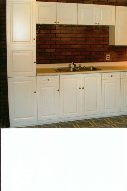 kitchen featuring backsplash, sink, and white cabinets