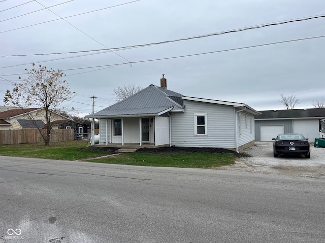 view of front of home featuring covered porch, a garage, an outbuilding, and a front lawn