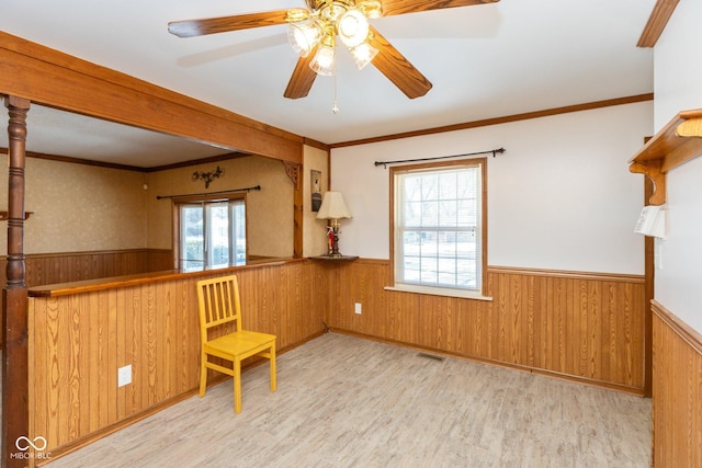 unfurnished room featuring ornamental molding, light wood-type flooring, and wood walls