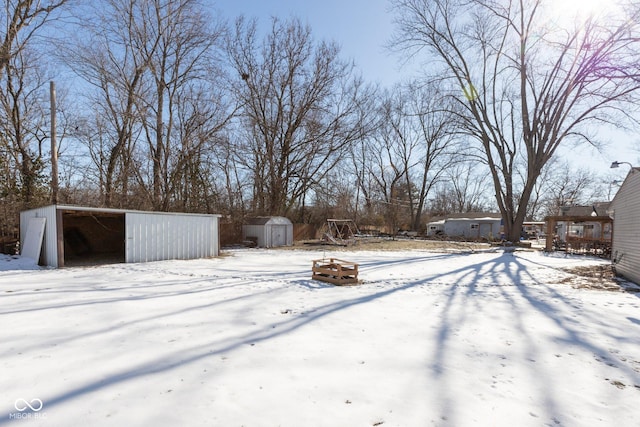 snowy yard featuring a storage unit