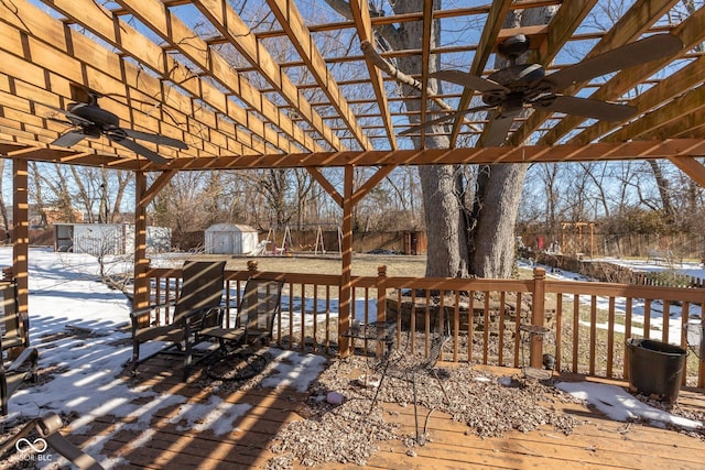 snow covered deck with a pergola, ceiling fan, and a storage unit