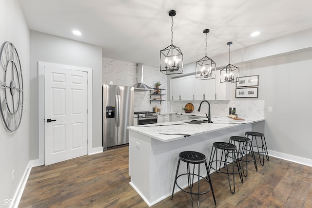 kitchen featuring kitchen peninsula, white cabinetry, decorative light fixtures, and appliances with stainless steel finishes