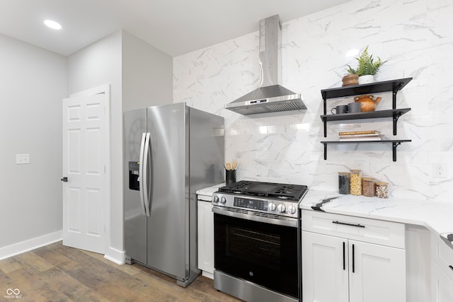 kitchen featuring white cabinets, wall chimney exhaust hood, dark hardwood / wood-style floors, light stone counters, and stainless steel appliances