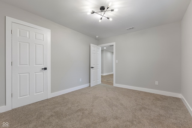 unfurnished bedroom featuring carpet floors and a notable chandelier