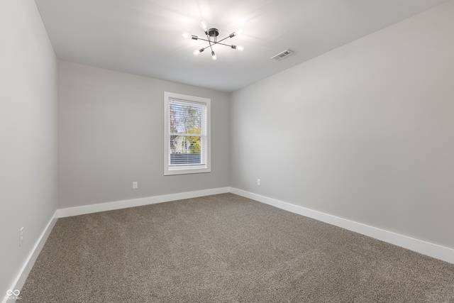 spare room featuring carpet and an inviting chandelier