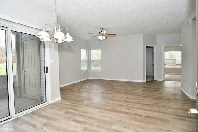 unfurnished room with ceiling fan with notable chandelier, light hardwood / wood-style floors, and a textured ceiling