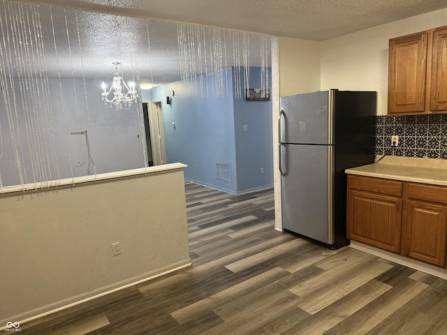 kitchen with a notable chandelier, dark hardwood / wood-style floors, stainless steel fridge, and tasteful backsplash