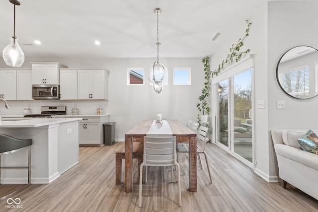 dining room featuring a chandelier, sink, and light hardwood / wood-style flooring