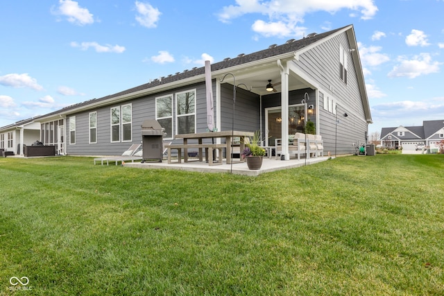 rear view of house featuring ceiling fan, a patio area, and a lawn