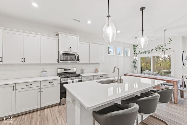 kitchen featuring decorative light fixtures, stainless steel appliances, white cabinetry, and sink