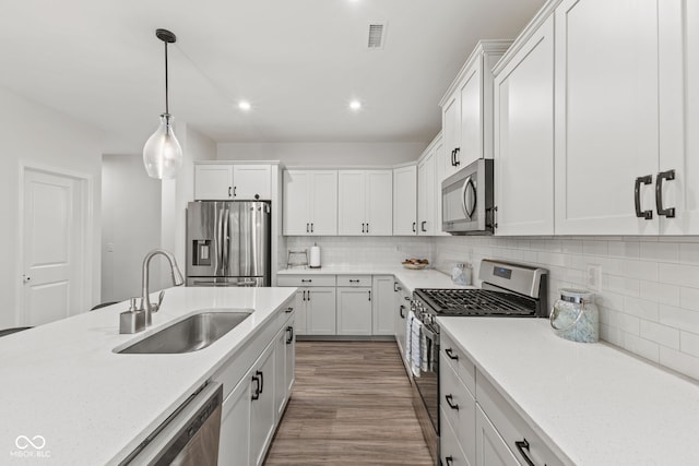 kitchen with white cabinetry, sink, stainless steel appliances, and hardwood / wood-style flooring