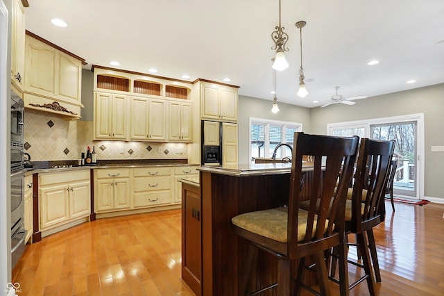 kitchen with decorative backsplash, ceiling fan, built in appliances, a center island, and hanging light fixtures