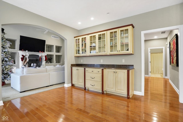 bar featuring cream cabinets, ceiling fan, built in features, and light hardwood / wood-style floors