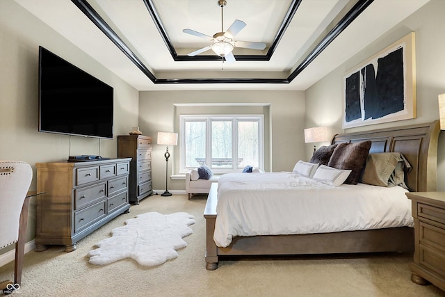 carpeted bedroom with a raised ceiling and ceiling fan