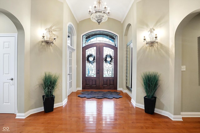 entryway featuring french doors, an inviting chandelier, high vaulted ceiling, and hardwood / wood-style flooring