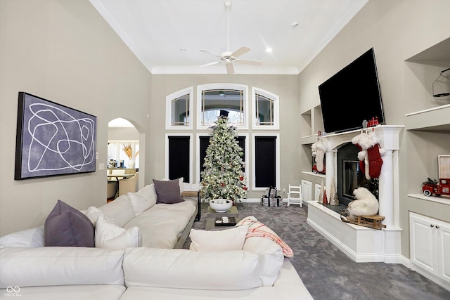 living room featuring ceiling fan, dark carpet, and ornamental molding