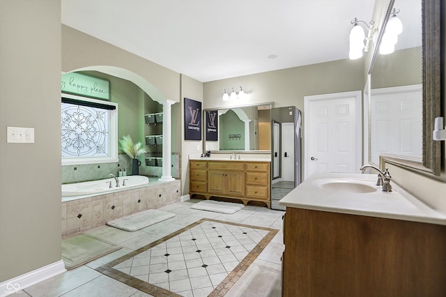 bathroom featuring vanity, a relaxing tiled tub, and tile patterned floors