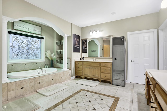 bathroom featuring tile patterned flooring, vanity, ornate columns, and tiled tub