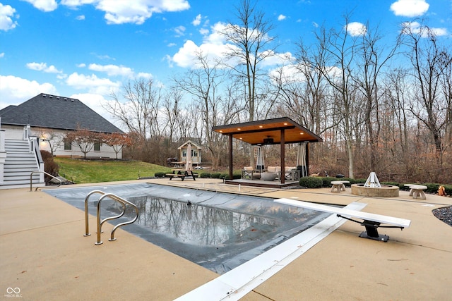 view of pool featuring a lawn, a diving board, a patio area, and an outdoor fire pit