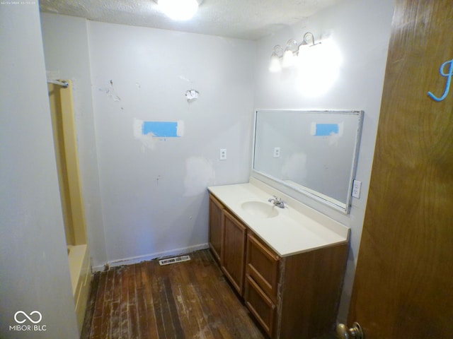 bathroom featuring a textured ceiling, vanity, wood-type flooring, and a tub