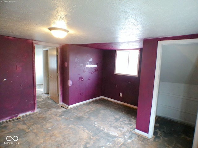 unfurnished room featuring lofted ceiling and a textured ceiling