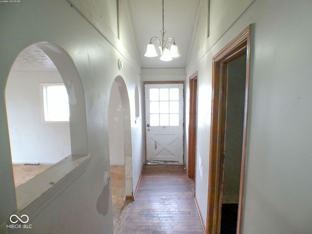 hallway featuring hardwood / wood-style floors, vaulted ceiling, and an inviting chandelier