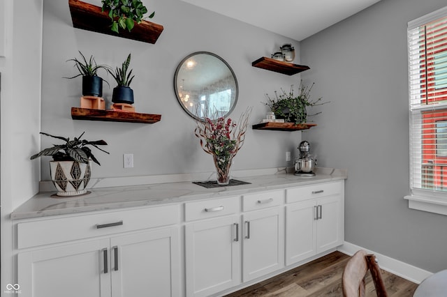 bar with white cabinets, light hardwood / wood-style flooring, a healthy amount of sunlight, and light stone counters