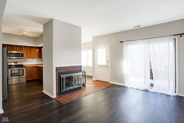 unfurnished living room featuring a textured ceiling, dark hardwood / wood-style floors, and a tiled fireplace