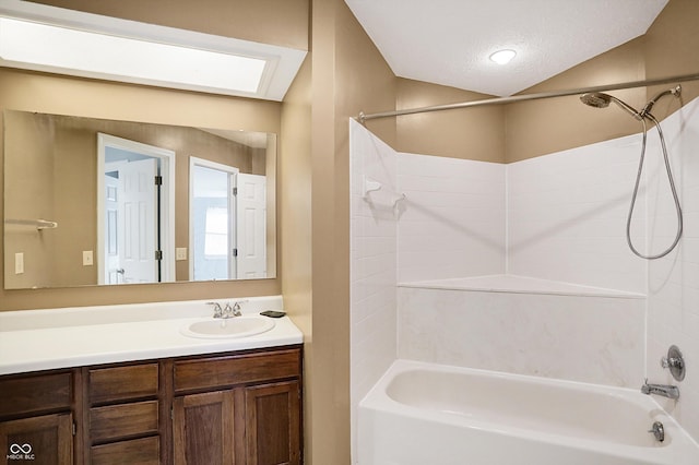 bathroom with vanity, shower / tub combination, a textured ceiling, and vaulted ceiling with skylight