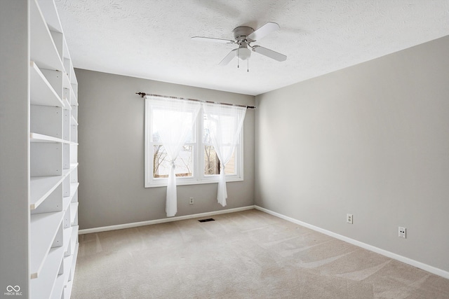 carpeted spare room featuring ceiling fan and a textured ceiling