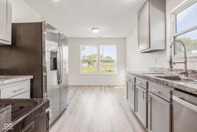 kitchen with gray cabinets, appliances with stainless steel finishes, light hardwood / wood-style flooring, and sink