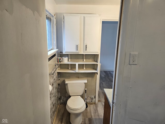 bathroom with hardwood / wood-style floors, tile walls, and toilet