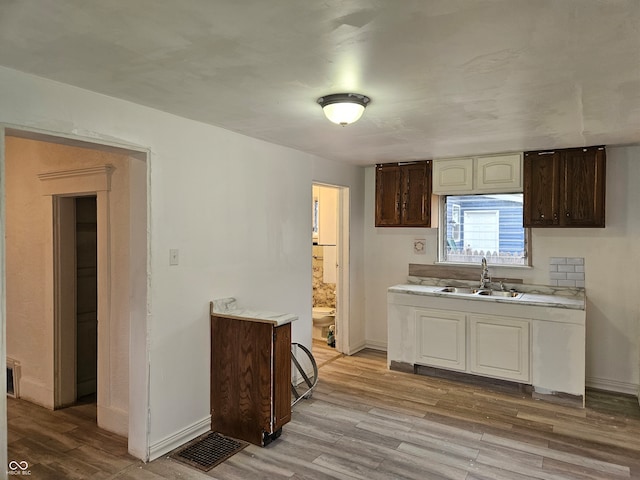 kitchen featuring dark brown cabinets, light hardwood / wood-style floors, and sink