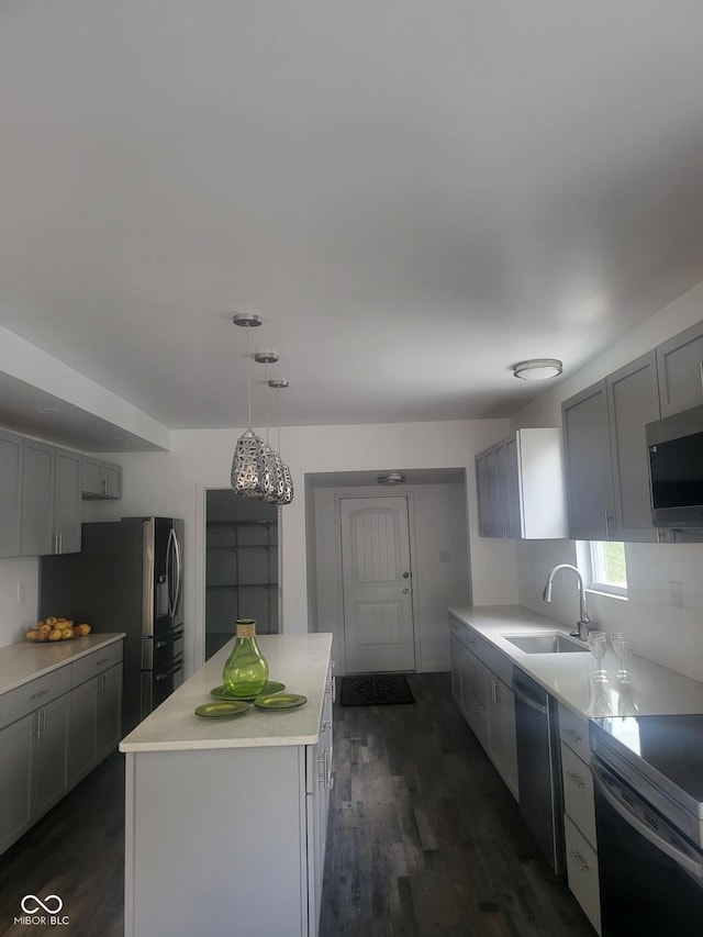 kitchen with appliances with stainless steel finishes, gray cabinets, a kitchen island, and sink