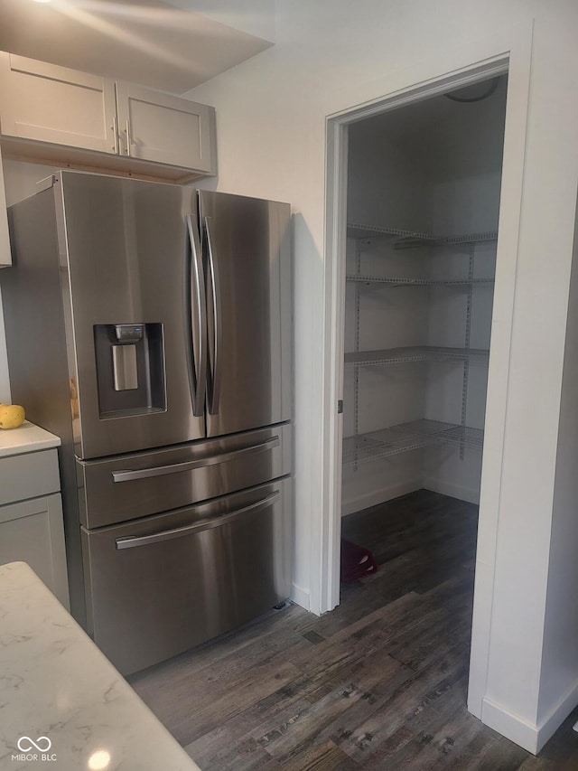 kitchen with light stone countertops, stainless steel fridge with ice dispenser, and dark hardwood / wood-style flooring