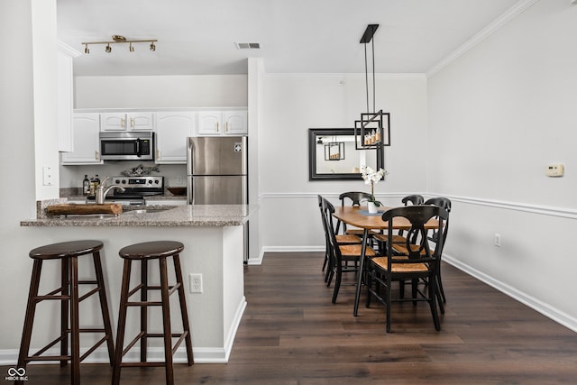 kitchen with kitchen peninsula, white cabinetry, stainless steel appliances, and dark hardwood / wood-style floors